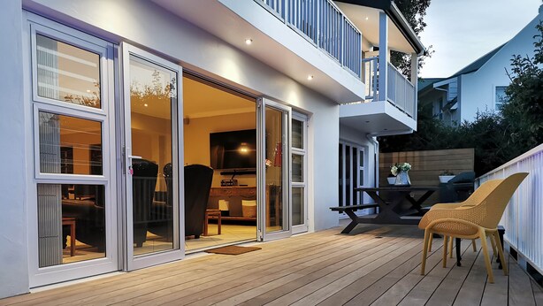 Una terrazza con idromassaggio, mobili da esterno e una porta scorrevole che dà su un ambiente interno.
