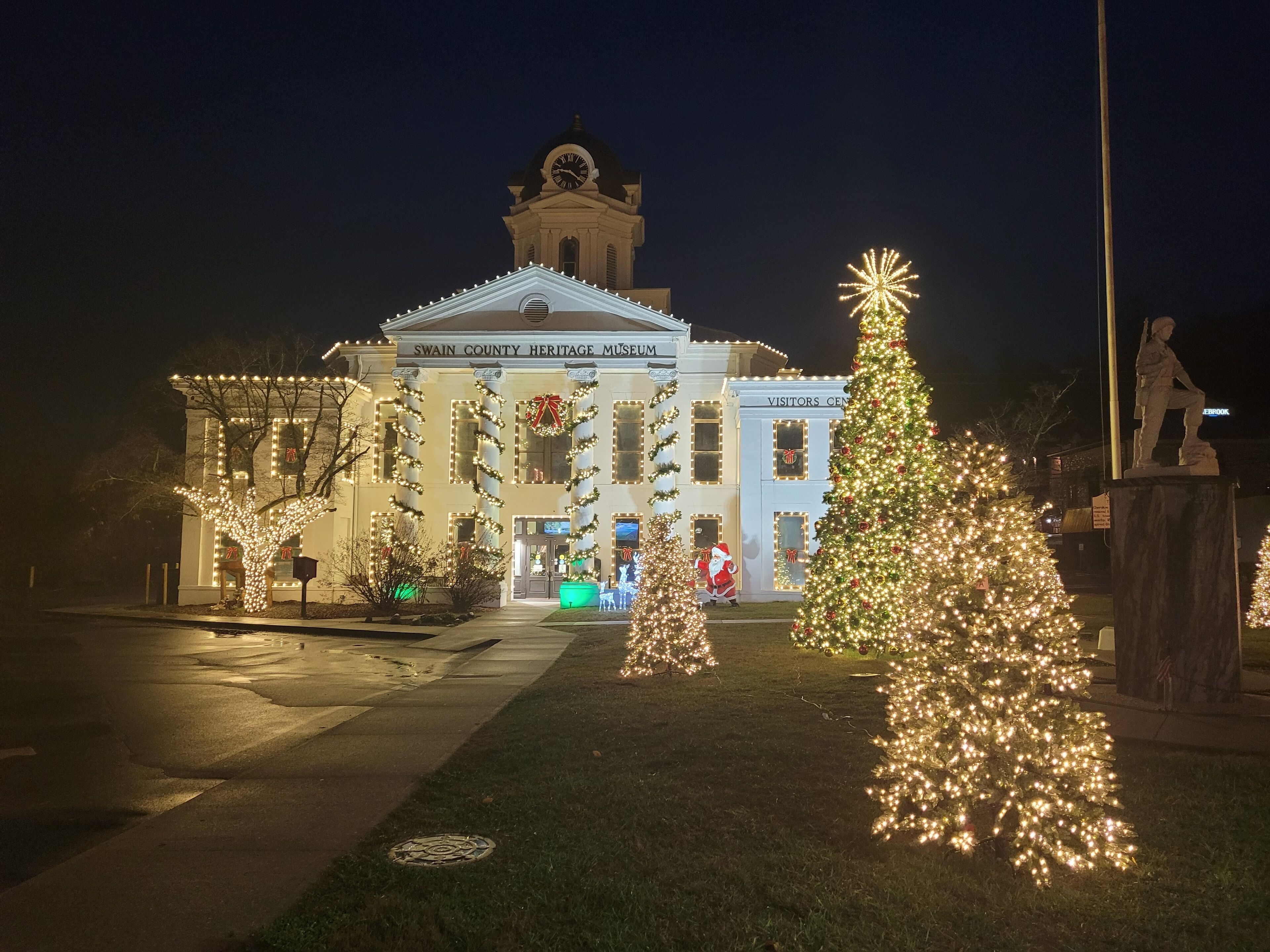 Un edificio de museo histórico con una cúpula y columnas, decorado con luces navideñas y un gran árbol de Navidad.