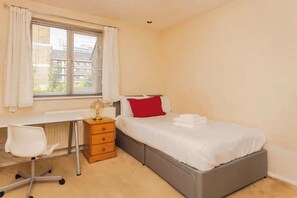A bedroom with a bed, a desk, and a chair.