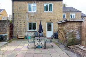 A brick house with a patio area featuring a table and chairs, a door, and a window.