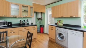 Una cocina con muebles de madera, lavadora y una mesa de comedor.