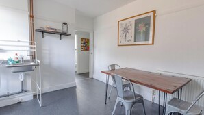 Een keuken met een houten tafel en stoelen, een witte gootsteen en een prikbord.