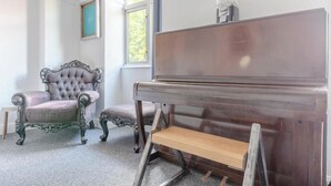 Een kamer met een vleugel, een fauteuil met knoopjes en een houten bank.