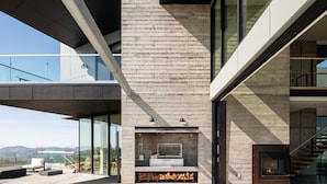 Moderni ulkotila, jossa on sisäänrakennettu takka, oleskelualue ja uima-allas.