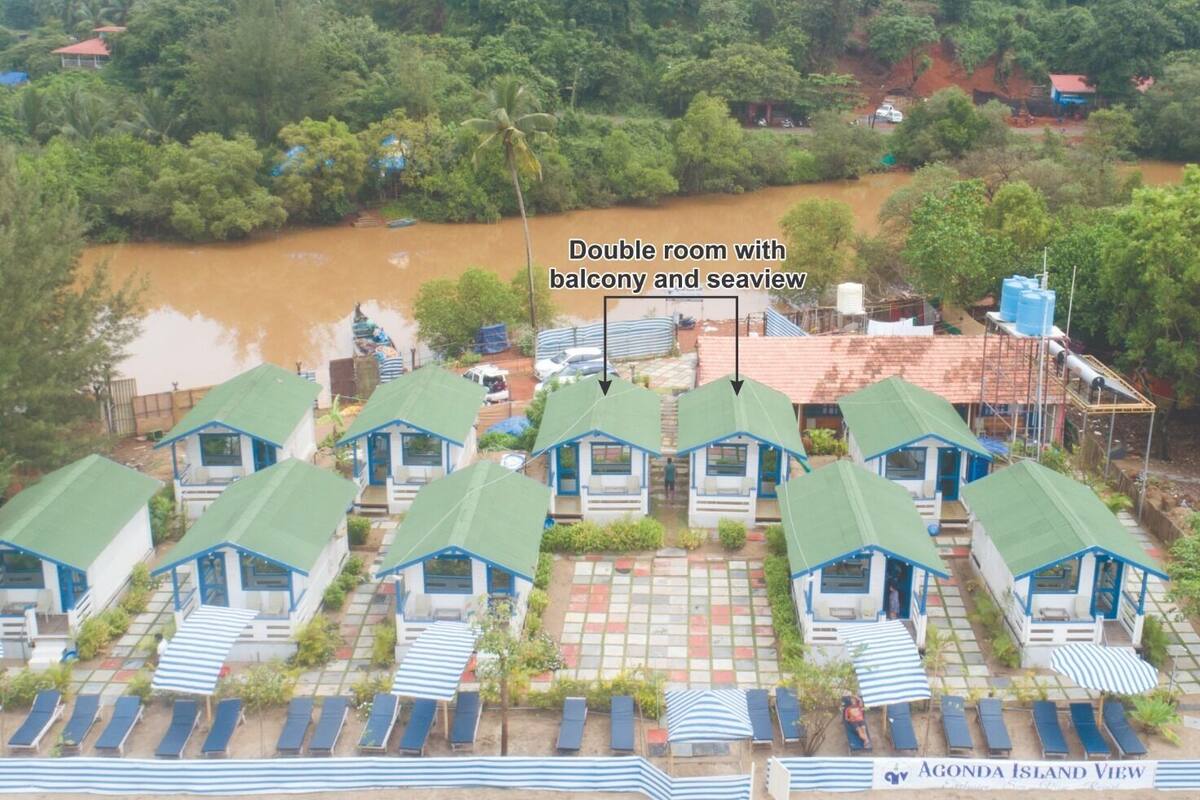 Reihenweise Bungalows mit Balkonen und Meerblick, umgeben von üppiger Vegetation und einem Fluss.