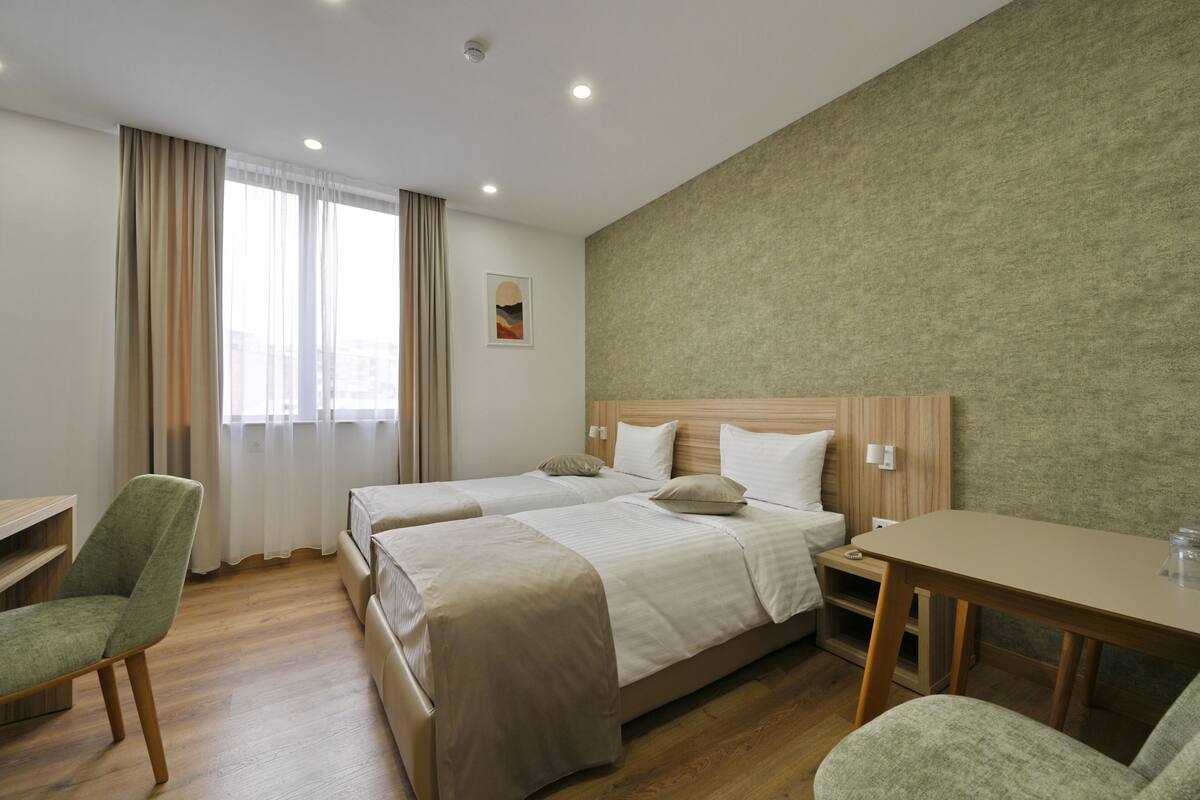 Habitación de hotel con dos camas, un escritorio y una silla.