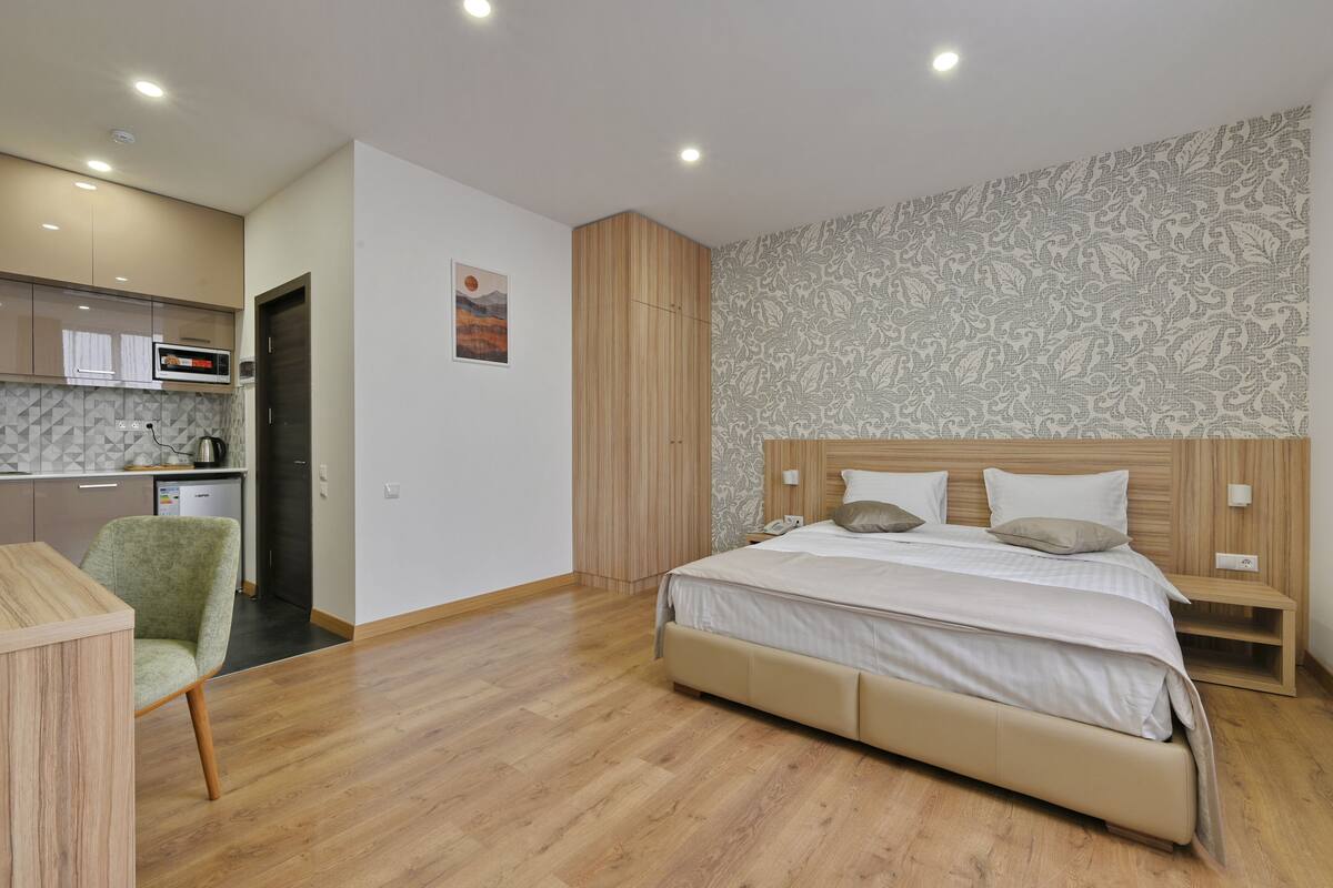 Un dormitorio moderno con una cama de madera, una mesita de noche pequeña y una silla.