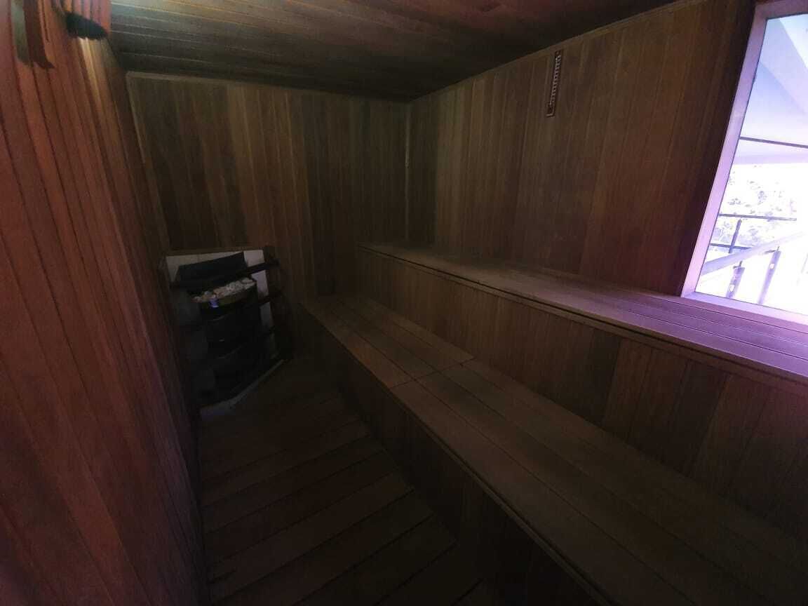 Un intérieur en bois avec un banc et une petite table, une fenêtre donnant sur un paysage agréable et une porte.