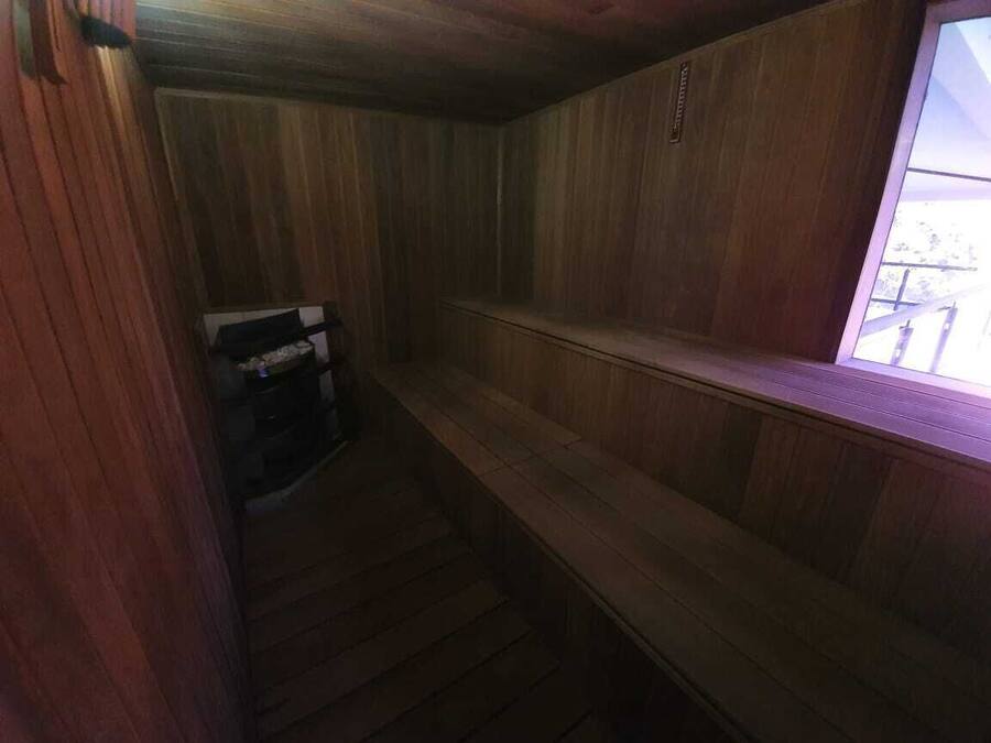 Un intérieur en bois avec un banc et une petite table, une fenêtre donnant sur un paysage agréable et une porte.