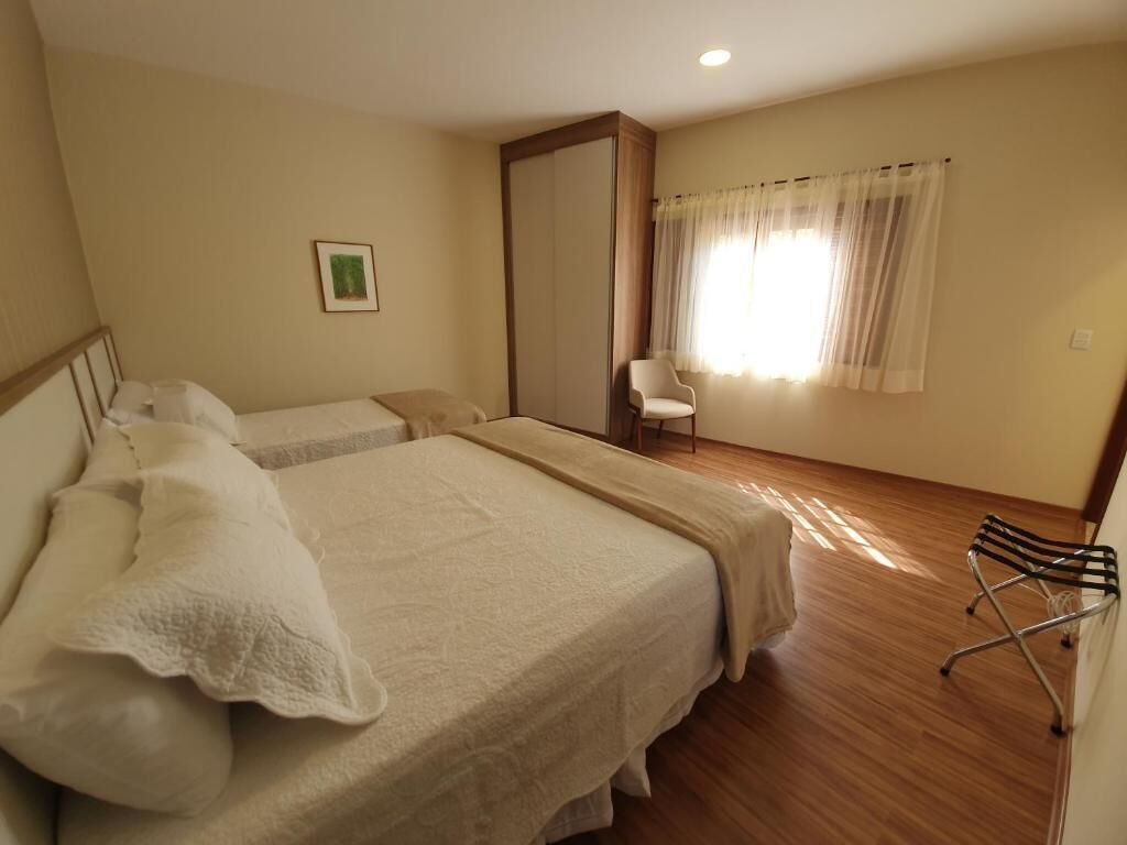 A bedroom with a large bed, a chair, and a wardrobe.