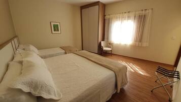 A bedroom with a large bed, a chair, and a wardrobe.
