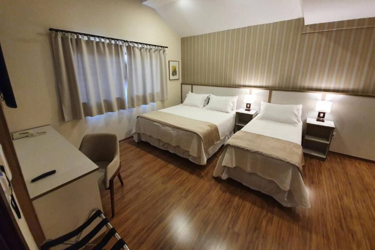 A hotel room with two beds, a desk, and a chair.