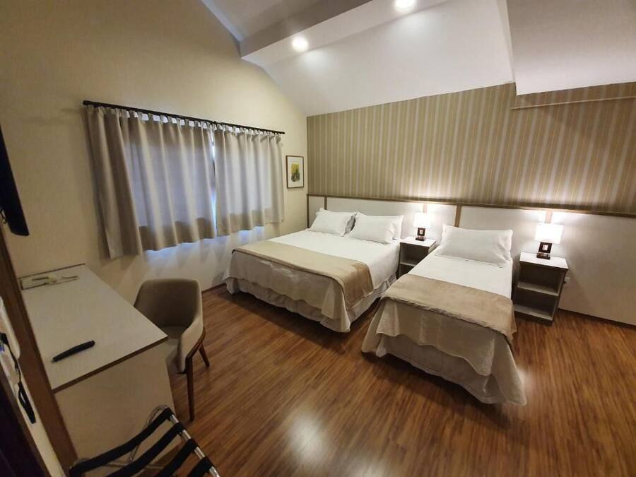 Ein Hotelzimmer mit zwei Betten, einem Schreibtisch und einem Stuhl.
