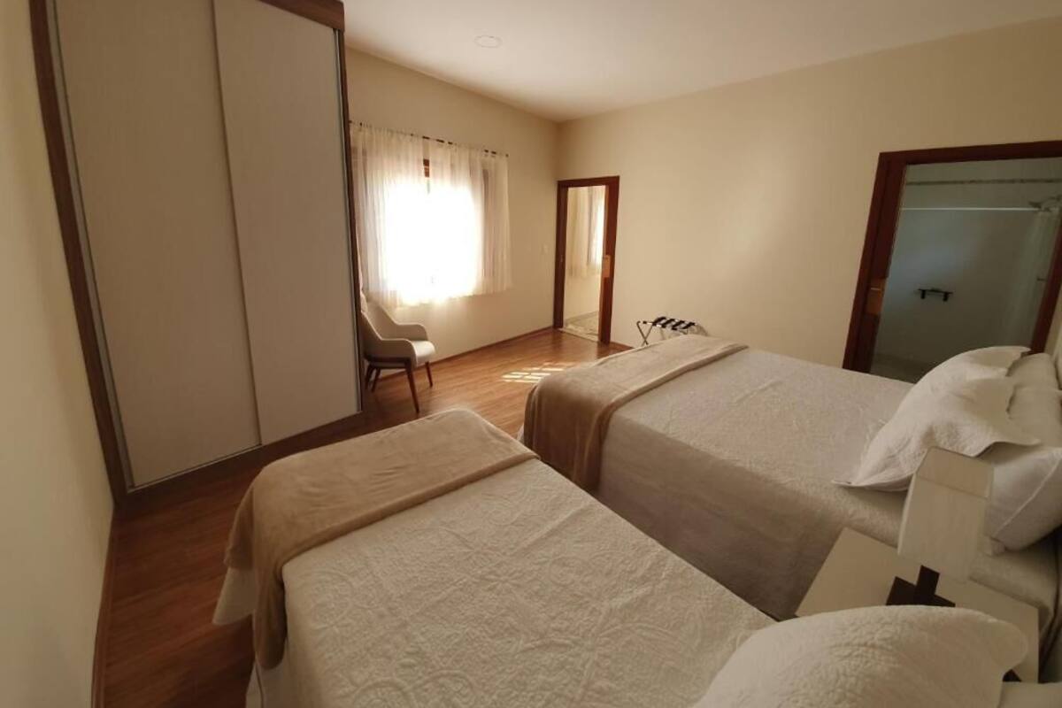 A hotel room with two beds, a desk, and a chair.