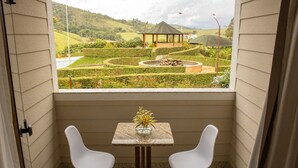 Habitación con vista a un jardín ajardinado, un pabellón y una mesa con dos sillas.