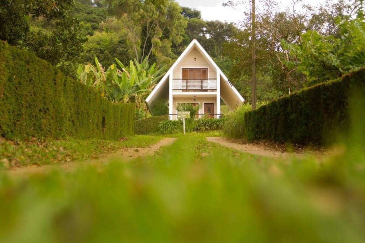 A house with a triangular roof, a balcony, and a pathway leading to it.