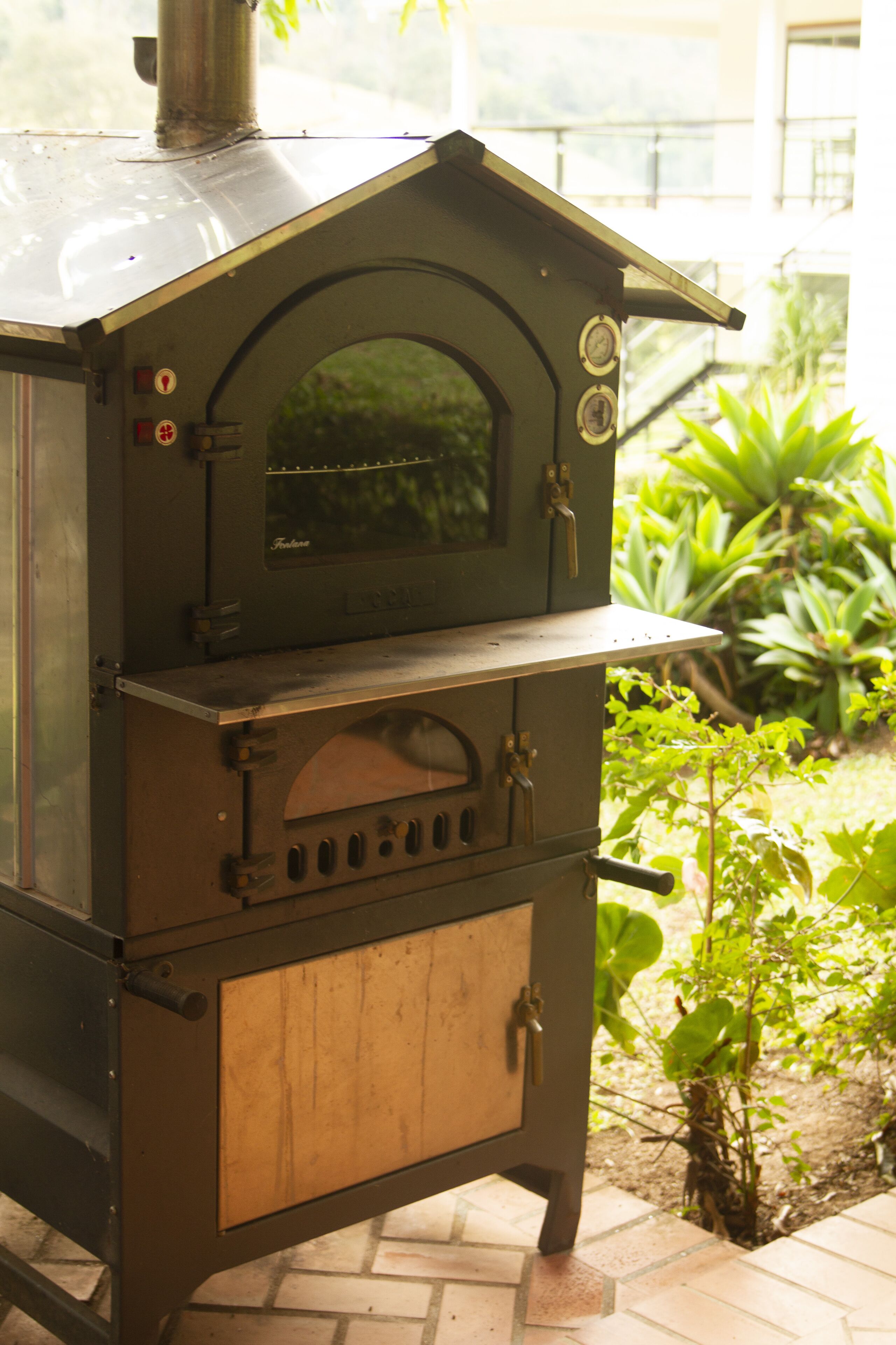 A vintage outdoor oven with a wooden door and a metal chimney.