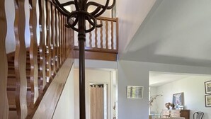 A spacious living area with a wooden staircase, a dining table, wicker chairs, and a sofa. - Between golf and beach (Pléneuf-Val-André)