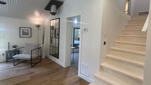 Una habitación amplia con suelo de madera, una escalera blanca y un diseño interior moderno.