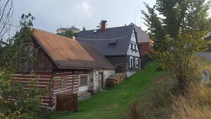 A traditional log cabin with a sloped roof, a stone wall, and a small garden area. - Terrace with gorgeous panorama in historic Rabstejn (Manetín)