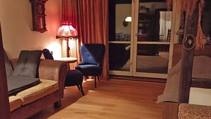 A cozy living room with a wooden floor, a sofa, a blue armchair, and a lamp. - Terrace with gorgeous panorama in historic Rabstejn (Manetín)