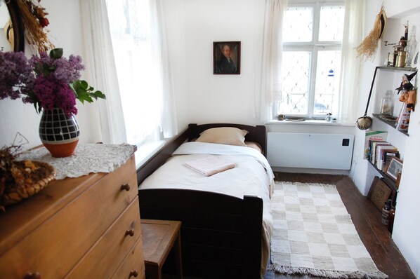 A bedroom with a bed, a dresser, a window with curtains, and a wall-mounted picture. - Terrace with gorgeous panorama in historic Rabstejn (Manetín)