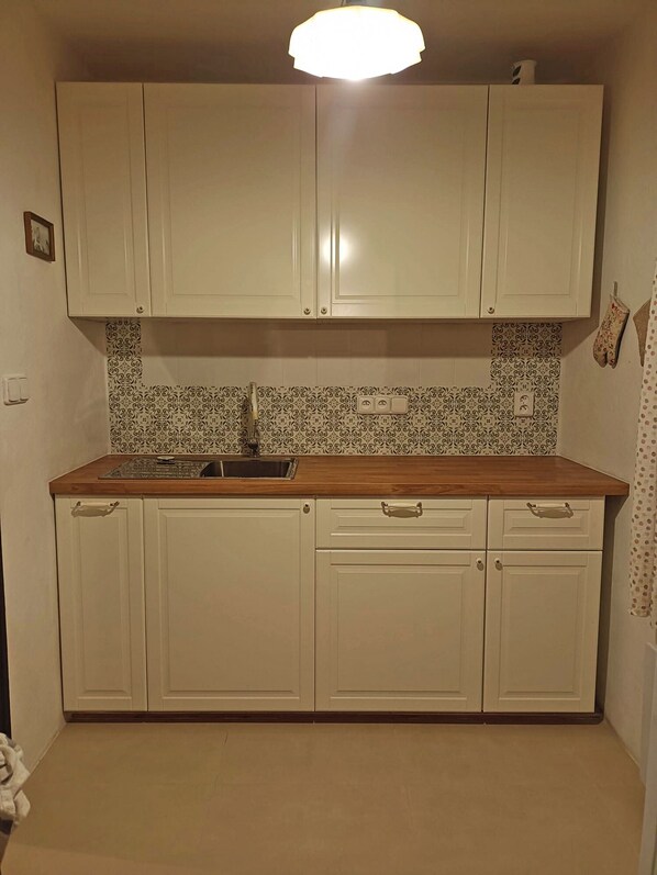 Cozinha com armários brancos, bancada de madeira e painel de fundo estampado.