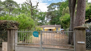 A gated area with a sign for 'hoomy' and a building with a yellow facade. - House between pine trees and beach (Saint-Brevin-les-Pins)