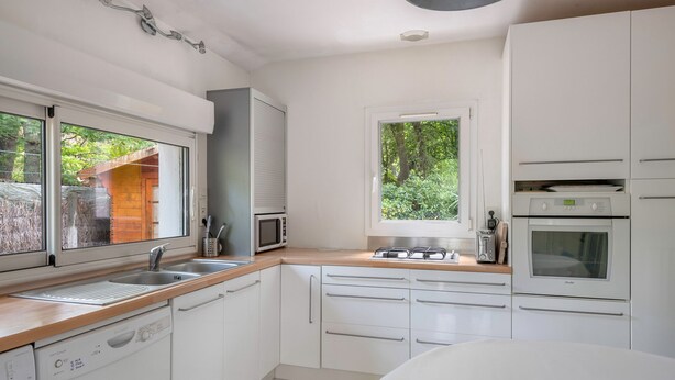 A modern kitchen with white cabinets, a built-in dishwasher, a microwave, a toaster, and an oven. - House between pine trees and beach (Saint-Brevin-les-Pins)