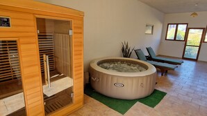 A sauna room with a wooden sauna, a hot tub labeled 'INTEX', and a seating area with two chairs. - Sabaudia Holiday home Il Maestrale (Lazio)