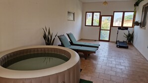 A room with a hot tub, two lounge chairs, a treadmill, and large windows. - Sabaudia Holiday home Il Maestrale (Lazio)