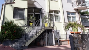 Un edificio de varios pisos con balcones, una escalera y plantas en macetas.