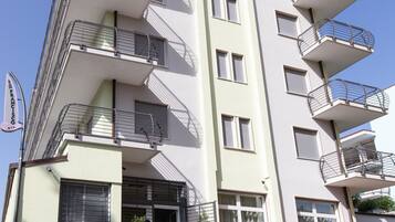 A multi-story building with balconies, a staircase, and potted plants.