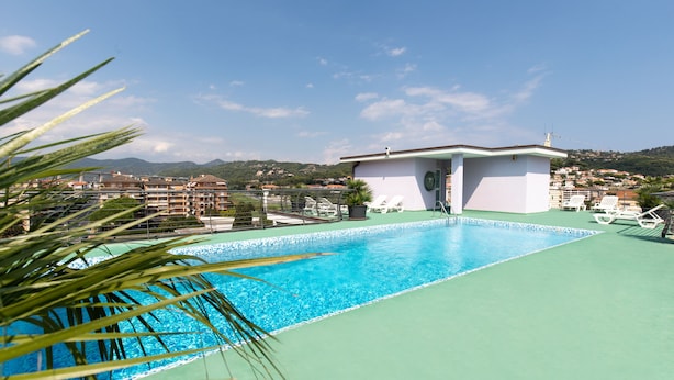 Una piscina en la azotea con vistas despejadas de los edificios y colinas circundantes.