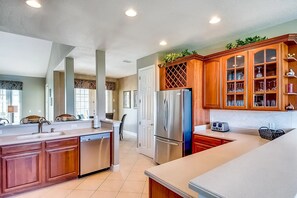 A modern kitchen with a central island, stainless steel appliances, wooden cabinets, and a backsplash.