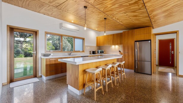 A modern kitchen with a central island, wooden cabinets, stainless steel appliances, and a red door. - Punka River Retreat - Porepunkah, Victoria (Porepunkah)
