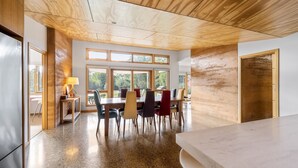 A modern dining area with a wooden ceiling, large windows, and a granite countertop. - Punka River Retreat - Porepunkah, Victoria (Porepunkah)