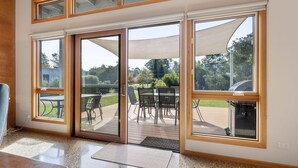 A modern room with large sliding glass doors leading to an outdoor patio area. - Punka River Retreat - Porepunkah, Victoria (Porepunkah)