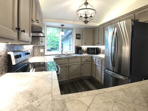 A modern kitchen with stainless steel appliances, a marble countertop, and a window providing natural light. - Upnorth with a dockslip (St. Helen)