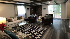 A spacious living room with a high ceiling, dark wooden beams, a glass coffee table, and a patterned rug. - Upnorth with a dockslip (St. Helen)