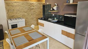 Cocina compacta con estufa a gas, horno integrado, encimera moderna y mesa de comedor con sillas.