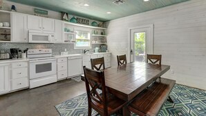 Une cuisine moderne avec des meubles blancs, une table à manger en bois et un tapis à motifs.