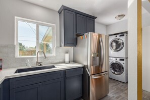 Enjoy cooking in this well-lit kitchen with a stainless steel refrigerator, washer and dryer, and sleek cabinetry.