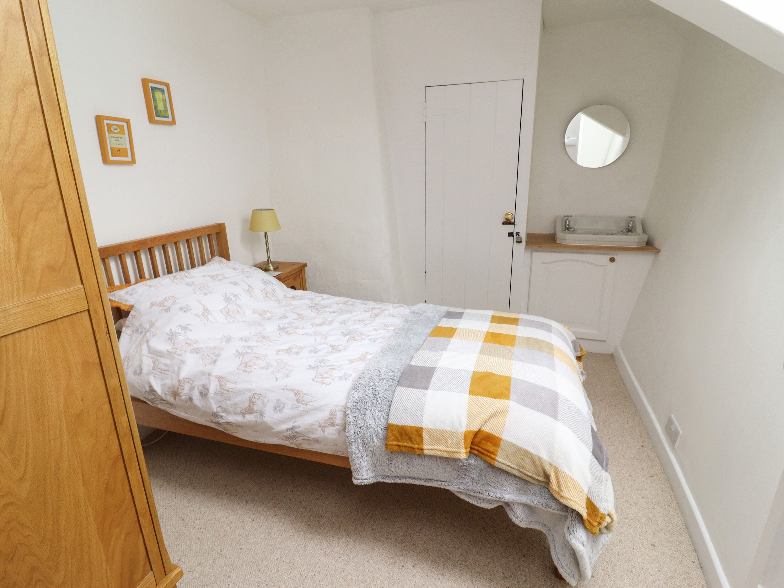 Quarto com cama, mesa de cabeceira, espelho e porta.
