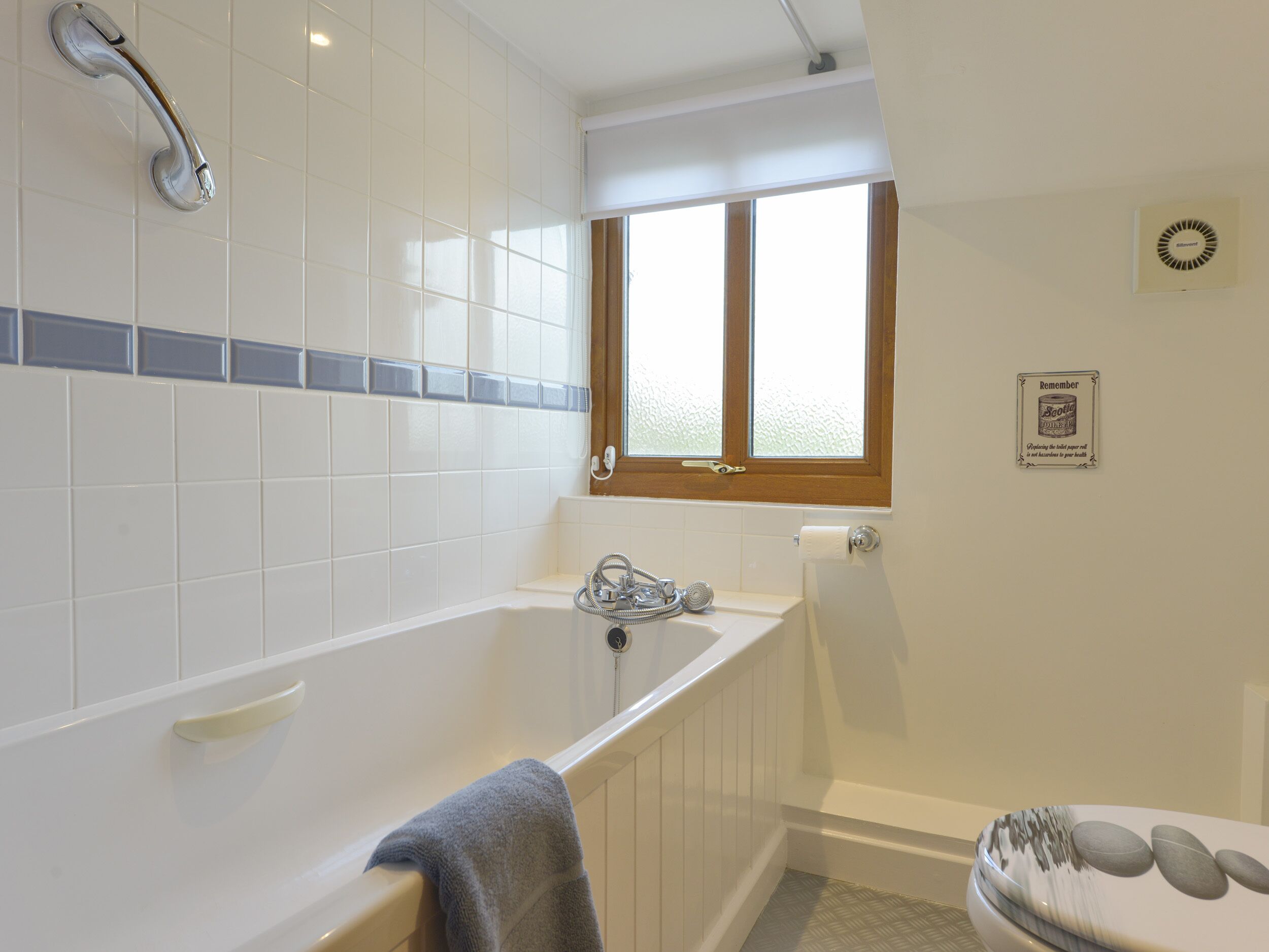 A bathroom with a bathtub, a shower, and a window.