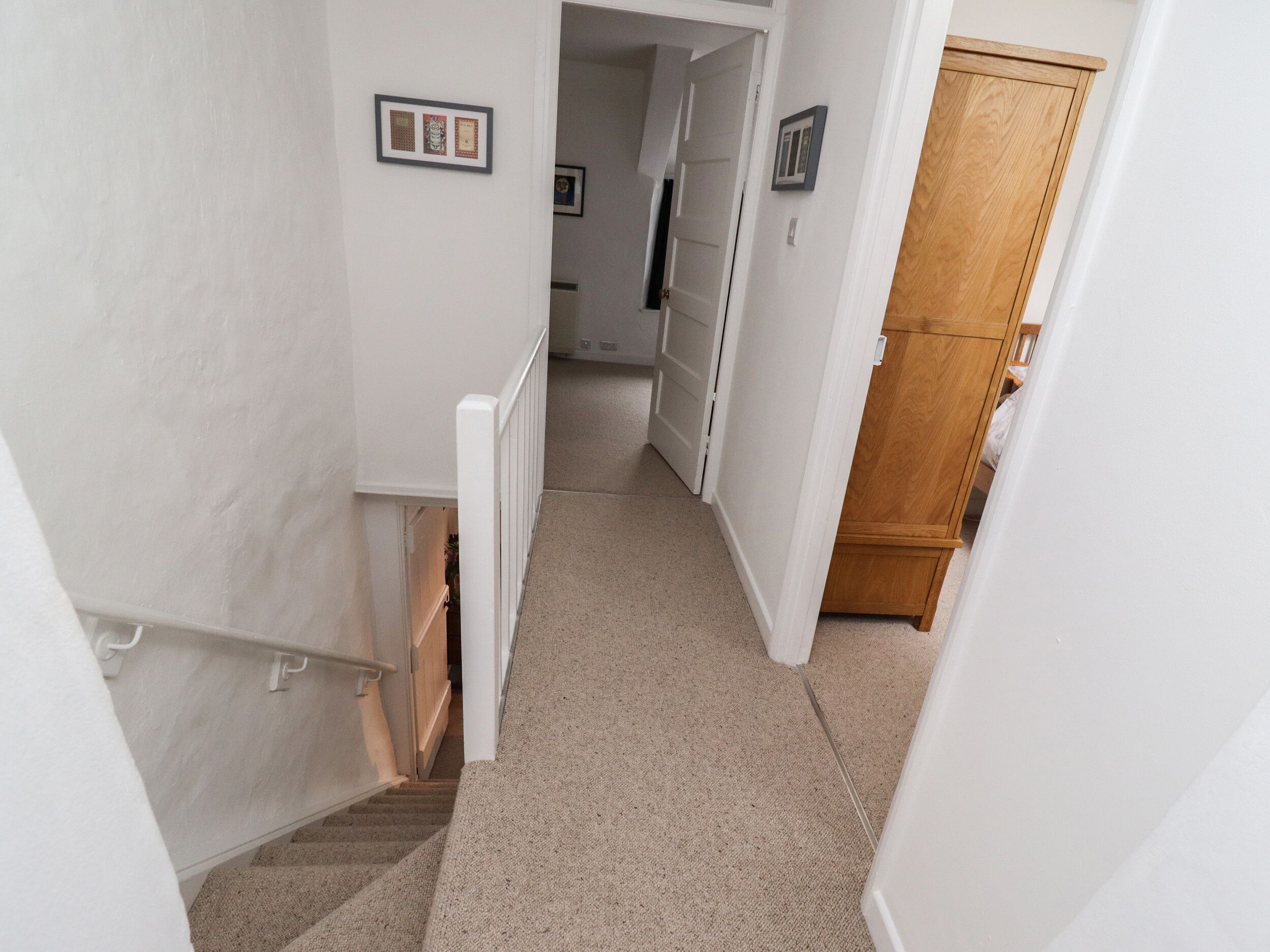 A narrow hallway with carpeted stairs leading to a door.