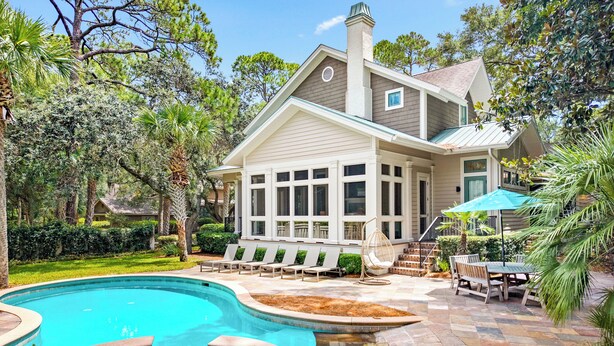 A house with a swimming pool, a covered patio, and a garden.