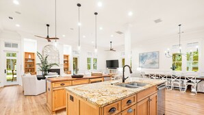 A spacious kitchen with wooden cabinets, granite countertops, and a central island with a sink.