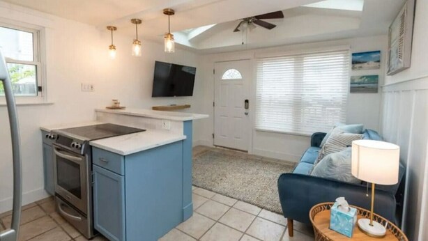 A compact living space with a kitchenette, a dining area, and a seating area with a sofa and a lamp.