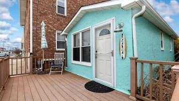 Situated on a wooden deck, this charming home offers a cozy porch with a bench and umbrella.